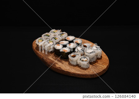 Creative minimalist display of assorted sushi rolls on a wooden platter against a dark backdrop, emphasizing vibrant colors and exquisite Japanese culinary art with a modern aesthetic. Creative minimalist display of assorted sushi rolls on a wooden platter against a dark backdrop, emphasizing vibrant colors and exquisite Japanese culinary art with a modern aesthetic. 126884140