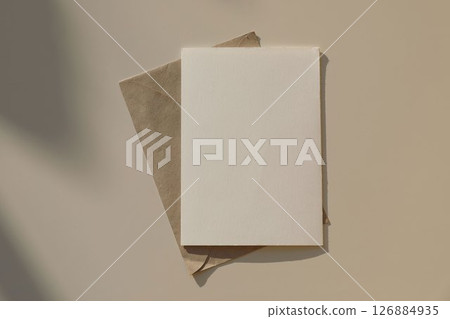 Empty greeting card, invitation mockup, craft envelope in sunlight, beige table background. Long shadows. Neutral web banner. Elegant wedding, modern minimal birthday template. Flat lay, top view. Empty greeting card, invitation mockup, craft envelope in sunlight, beige table background. Long shadows. Neutral web banner. Elegant wedding, modern minimal birthday template. Flat lay, top view. 126884935