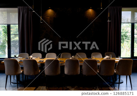 Dining room interior with long wooden table surrounded by grey chairs Dining room interior with long wooden table surrounded by grey chairs 126885171
