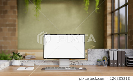The white screen computer on marble laminate wooden working desk in an office with green wall. 126885218