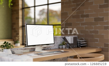 The white screen computer on marble laminate wooden working desk in an office with brick wall. The white screen computer on marble laminate wooden working desk in an office with brick wall. 126885219
