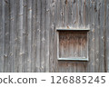 Wooden planked wall and small closed wooden window 126885245