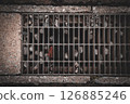 Detail of asphalt drain with clogged pebbles and fallen leaves 126885246