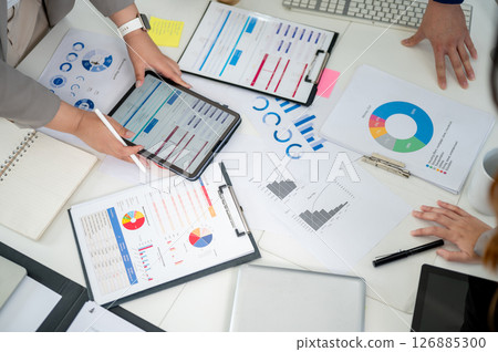 Top view of a working desk with a pair of hand holding a digital tablet and scattered documents. Top view of a working desk with a pair of hand holding a digital tablet and scattered documents. 126885300