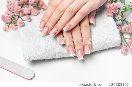 Woman showing her french manicure on a white towel Woman showing her french manicure on a white towel 126885502