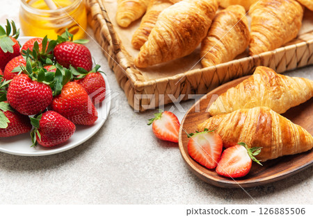 Delicious french croissants with fresh strawberries and honey for breakfast Delicious french croissants with fresh strawberries and honey for breakfast 126885506