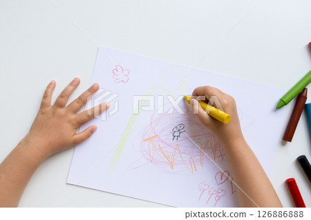 Child drawing. Young hand coloring with crayons on white paper 126886888