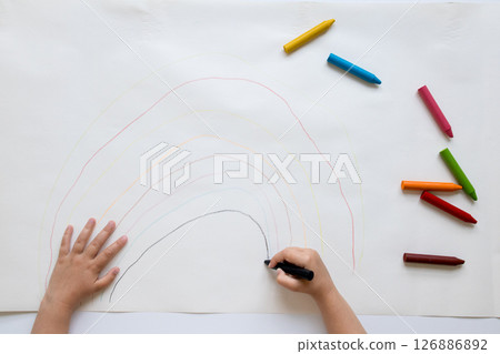 Child drawing colorful rainbow with crayons on paper 126886892