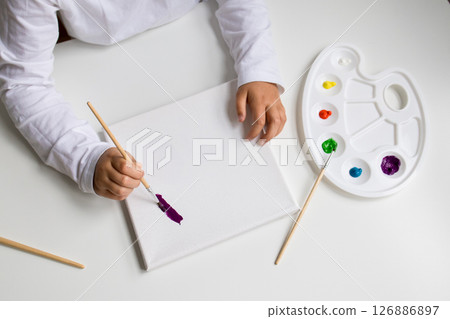 Child painting on canvas with colorful palette and brush Child painting on canvas with colorful palette and brush 126886897
