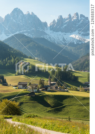 Visit Italy. Morning light spills over Santa Maddalena quaint village and sharp Dolomite peaks, a vertical frame of alpine calm and storybook charm 126888317