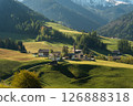 Visit Italy. Santa Maddalena wakes in soft golden light, church spire rising beneath the jagged Dolomites, a peaceful morning in the heart of South 126888318