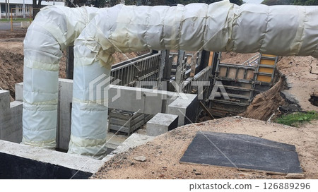 Insulated pipes emerging from underground concrete structure Insulated pipes emerging from underground concrete structure 126889296