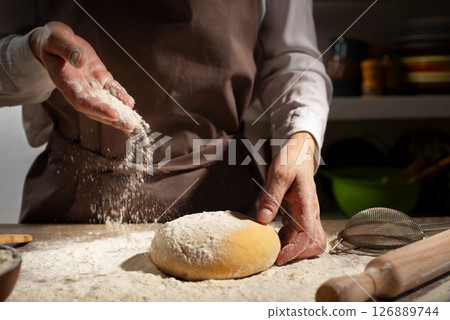 Baking concept. Caucasian female hands throwing flour at the dough. 126889744