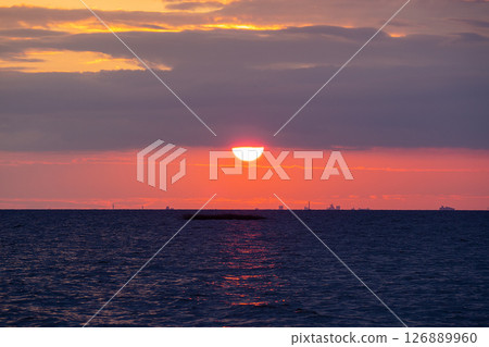 Scenic sunset over the sea. The sun is peeking out from behind the clouds. 126889960