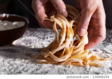 Caucasian female hands holding raw fettuccine noodles after drying 126890294