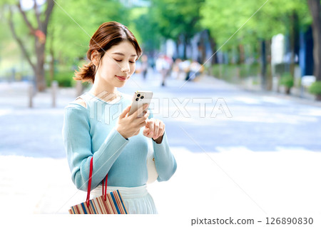 A stylish young woman operating a smartphone while shopping 126890830