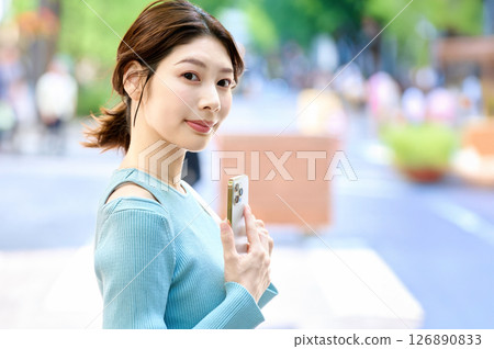 A stylish young woman operating a smartphone while shopping A stylish young woman operating a smartphone while shopping 126890833