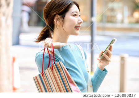 A stylish young woman operating a smartphone while shopping 126890837