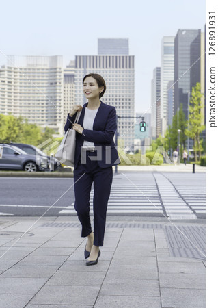 年輕的女商人穿過辦公區，垂直位置 126891931