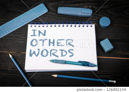 In Other Words. Notepad and blue stationery on a black wooden texture background In Other Words. Notepad and blue stationery on a black wooden texture background 126892134
