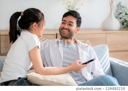 Young asian couple relax sitting on sofa looking smartphone together in living room. Young asian couple relax sitting on sofa looking smartphone together in living room. 126892210