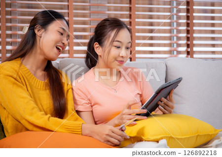 Two young asian woman sitting on sofa using tablet computer shopping online with credit card. 126892218