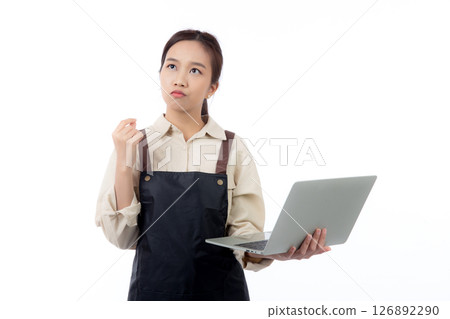 Portrait young asian business woman wearing apron holding laptop computer isolated. Portrait young asian business woman wearing apron holding laptop computer isolated. 126892290
