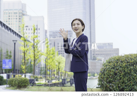 年輕女商人走過辦公區時揮手致意 126892413