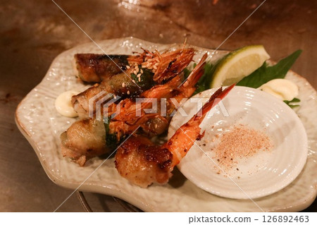 close up of grilled prawns wrapped with tofu skin on a plate with salt on the side 126892463