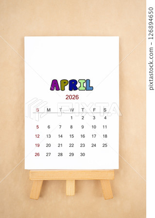 Calendar page for April 2026 with wood easel on old brown background. 126894650