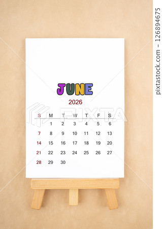 Calendar page for June 2026 with wood easel on old brown background. 126894675