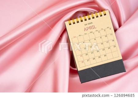 April 2026 craft brown paper desk calendar on pink silk textile background. April 2026 craft brown paper desk calendar on pink silk textile background. 126894685