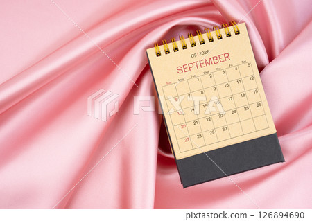 September 2026 craft brown paper desk calendar on pink silk textile background. September 2026 craft brown paper desk calendar on pink silk textile background. 126894690