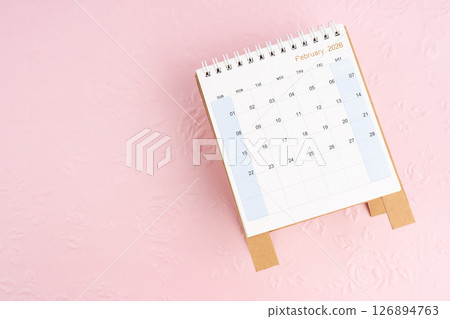 February 2026 desk calendar on pink paper with flower pattern background. February 2026 desk calendar on pink paper with flower pattern background. 126894763