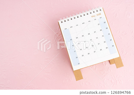 May 2026 desk calendar on pink paper with flower pattern background. 126894766