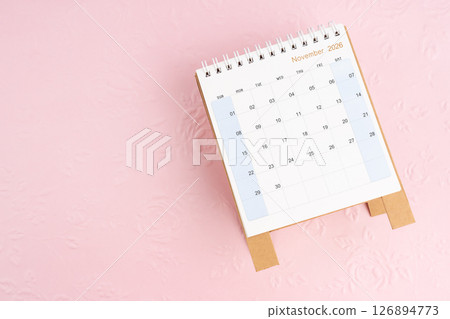 November 2026 desk calendar on pink paper with flower pattern background. 126894773