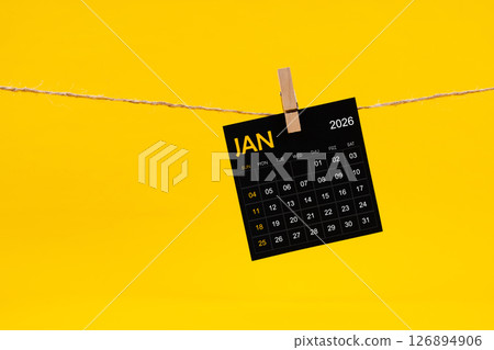January 2026 black calendar hanged with brown rope on yellow background. January 2026 black calendar hanged with brown rope on yellow background. 126894906