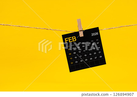 February 2026 black calendar hanged with brown rope on yellow background. February 2026 black calendar hanged with brown rope on yellow background. 126894907