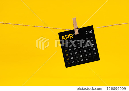 April 2026 black calendar hanged with brown rope on yellow background. April 2026 black calendar hanged with brown rope on yellow background. 126894909