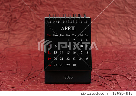 April 2026, Front view black desk calendar on crumpled red paper. April 2026, Front view black desk calendar on crumpled red paper. 126894913