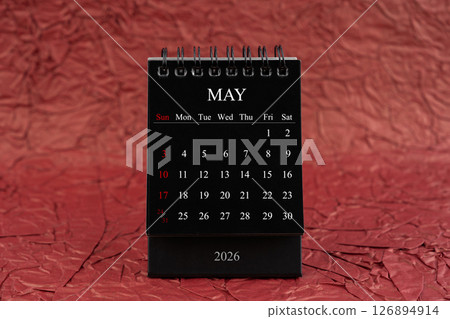May 2026, Front view black desk calendar on crumpled red paper. May 2026, Front view black desk calendar on crumpled red paper. 126894914