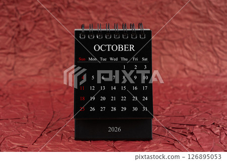 October 2026, Front view black desk calendar on crumpled red paper. 126895053