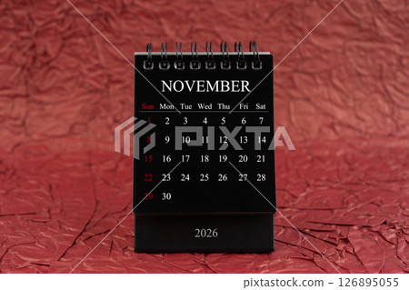 November 2026, Front view black desk calendar on crumpled red paper. November 2026, Front view black desk calendar on crumpled red paper. 126895055