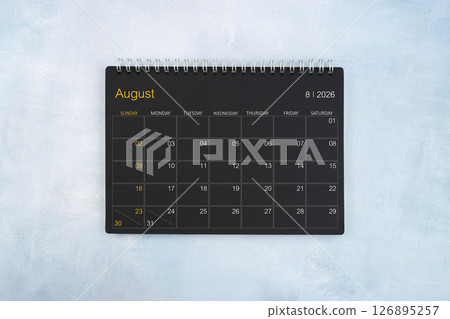 Blank calendar for August 2026, Black spiral desktop calendar on wooden background. 126895257