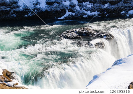horizontal photo took in Gullfoss Falls, Hvita river, Golden Circle, Reykjavik, Iceland. A waterfall cascading over rocky cliffs into a river below with snow covered areas and a clear blue sky horizontal photo took in Gullfoss Falls, Hvita river, Golden Circle, Reykjavik, Iceland. A waterfall cascading over rocky cliffs into a river below with snow covered areas and a clear blue sky 126895816