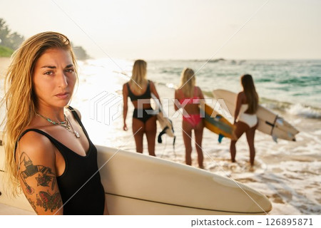 Blonde girl with surfboard on sunny beach. Women in swimsuits with surfboards by ocean. Golden sand, sunset waves. Surf lifestyle, summer vibes, water sports, active vacation, outdoor adventure. Blonde girl with surfboard on sunny beach. Women in swimsuits with surfboards by ocean. Golden sand, sunset waves. Surf lifestyle, summer vibes, water sports, active vacation, outdoor adventure. 126895871