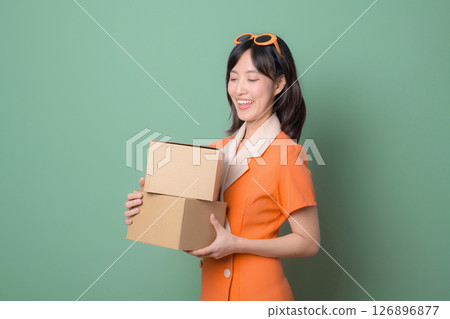 Southeast asian woman holding cardboard boxes with happy expression represents internet online shopping and delivery service against green background Southeast asian woman holding cardboard boxes with happy expression represents internet online shopping and delivery service against green background 126896877