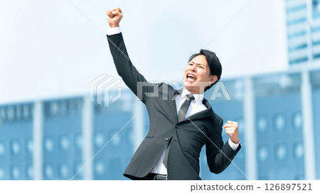 A cheerful male businessman doing a fist pump A cheerful male businessman doing a fist pump 126897521