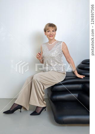 Smiling woman sitting on sofa in bright sunny room. Looking at camera. Vertical photo. High quality photo Smiling woman sitting on sofa in bright sunny room. Looking at camera. Vertical photo. High quality photo 126897566