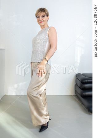 Smiling woman in festive clothes against gray wall in bright sunny room. Vertical photo. High quality photo Smiling woman in festive clothes against gray wall in bright sunny room. Vertical photo. High quality photo 126897567